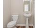 Bright bathroom with a pedestal sink, wood look floors, and a decorative mirror at 161 Walking Path Pl, Hillsborough, NC 27278