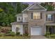 Two-story townhome showcases a blend of brick and siding, enhanced by flowering plants and an attached garage at 161 Walking Path Pl, Hillsborough, NC 27278