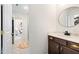 Bathroom featuring a wood vanity cabinet, round mirror and view of the tiled shower and bedroom at 211 Education Dr, Spring Lake, NC 28390
