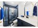 Bright bathroom featuring dark blue cabinets and a sleek glass shower with blue tile at 211 Education Dr, Spring Lake, NC 28390