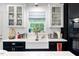 Bright kitchen with black and white cabinets, farmhouse sink, and a window overlooking a wooded area at 211 Education Dr, Spring Lake, NC 28390