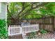 Charming backyard retreat featuring a white picket fence, bench swing under mature trees, and lush landscaping at 2112 Tulare Ct, Raleigh, NC 27612