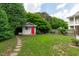 Spacious backyard featuring lush greenery, stone pathway, shed with bright red door and mature trees offering shade at 2112 Tulare Ct, Raleigh, NC 27612