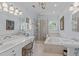 Well-lit bathroom featuring double sinks, vanity, glass shower, and soaking tub at 2112 Tulare Ct, Raleigh, NC 27612