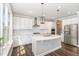 Modern white kitchen with stainless steel appliances, a large island with a sink, and designer pendant lighting at 2885 Farmhouse Dr, Apex, NC 27502