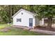 Side exterior featuring a white garage and shed or small home with blue doors, set in backyard at 300 Plantation Rd, Clayton, NC 27520