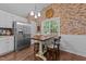 Eat-in kitchen with modern stainless steel appliances, white cabinets, and a rustic wood table set against a brick wall at 300 Plantation Rd, Clayton, NC 27520