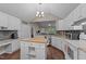 Kitchen featuring modern appliances, an island, granite counters, white cabinetry, and a vaulted ceiling at 300 Plantation Rd, Clayton, NC 27520