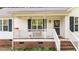 Inviting front porch with a seating area, white railings, and brick stairs leading to the entrance at 300 Plantation Rd, Clayton, NC 27520