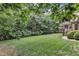 Lush backyard with manicured lawn, mature trees, and rear view of house and porch at 3007 Krogen Ct, Creedmoor, NC 27522