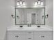 Bathroom with double sinks, white cabinetry, and a large mirror with green tile border at 3007 Krogen Ct, Creedmoor, NC 27522