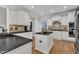 Open kitchen with white cabinets, black countertops, an island, tiled backsplash, stainless steel appliances and hardwood floors at 3007 Krogen Ct, Creedmoor, NC 27522