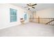 Large bonus room with neutral carpet, three windows, ceiling fan, and wood banister at 3025 Creek Moss Ave, Wake Forest, NC 27587