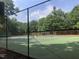 Fenced tennis court surrounded by trees, offering an active lifestyle at 305 Burkwood Ln, Raleigh, NC 27609