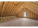Unfinished attic with exposed rafters, plywood floor, and a window providing natural light at 310 Cross Lake, Fuquay Varina, NC 27526