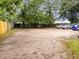 Large parking area behind property with gravel, surrounded by mature trees and wooden fence at 313 Colleton Rd, Raleigh, NC 27610