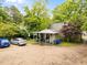 Rear view of property with a spacious parking area and a covered patio, nestled amongst mature trees at 313 Colleton Rd, Raleigh, NC 27610