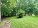 Expansive backyard with a manicured lawn, complemented by mature trees and natural rock features, creating a private retreat at 327 Beavertail Rd, Henderson, NC 27537
