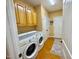 Functional laundry room with a modern washer and dryer, cabinets, and hardwood floors at 327 Beavertail Rd, Henderson, NC 27537