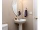 Half bath with a pedestal sink, round mirror, and neutral paint for a simple and functional design at 3507 Portico Ln, Durham, NC 27703