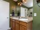 Bathroom with double sinks, wood cabinets, large mirror, updated light fixture and shower at 3507 Portico Ln, Durham, NC 27703