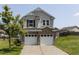 Two-story home with vinyl siding, brick base, and two-car garage beneath a blue sky on a sunny day at 3507 Portico Ln, Durham, NC 27703