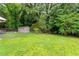 Large backyard with a fenced perimeter, mature trees, and a small storage shed at 3515 Luna Ln, Durham, NC 27705