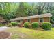 Well-manicured lawn, mature trees and a traditional brick ranch house in a wooded setting at 3515 Luna Ln, Durham, NC 27705