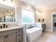 Relaxing bathroom showcasing a modern soaking tub, separate vanities, and wood-look tile flooring at 4104 Bankshire Ln, Raleigh, NC 27603