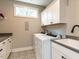 Well-lit laundry room with patterned floors, white cabinets, and a sink near a front-load washer and dryer at 4104 Bankshire Ln, Raleigh, NC 27603