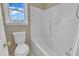 Bathroom with white toilet and a shower featuring tiled walls and a bright window at 430 Sir David Dr, Zebulon, NC 27597