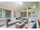 Bright sunroom with wicker furniture, white sofas with blue pillows and natural light at 5 Wembley Ct, Durham, NC 27705