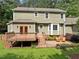 Expansive backyard featuring a wooden deck, brick patio with seating, and lush green lawn at 5116 Knaresborough Rd, Raleigh, NC 27612