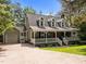 View of the home with a long driveway leading up to a charming green home with a white porch at 5116 Knaresborough Rd, Raleigh, NC 27612
