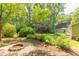 Well-manicured backyard with a charming garden, surrounded by mature trees, and outdoor dining at 520 Brittany Bay W, Raleigh, NC 27614