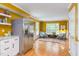 Bright living room with yellow walls, hardwood floors, and stainless steel refrigerator near seating area with stylish rug at 520 Brittany Bay W, Raleigh, NC 27614