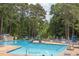 Community pool featuring a slide, lounge chairs, and a surrounding wooded area, perfect for relaxation and recreation at 520 Brittany Bay W, Raleigh, NC 27614