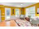 A sitting area boasts sunny yellow walls, colorful rug, wood flooring, and bright natural light at 520 Brittany Bay W, Raleigh, NC 27614