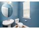 Stylish powder room features a pedestal sink, modern fixtures and calming blue walls at 520 Camden Yards Way, Cary, NC 27519