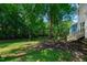 Serene backyard with mature trees, grassy areas, and a partial view of the house with a small deck at 5236 Turf Grass Ct, Raleigh, NC 27610