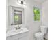 Bright bathroom features a white vanity, toilet, and a mirror reflecting a view into another room at 5236 Turf Grass Ct, Raleigh, NC 27610