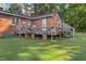 Exterior view showcasing the back of the brick house, featuring a wooden deck and ample yard space at 586 New Hope Church Rd, Apex, NC 27523