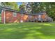 View of the home's backyard featuring a wooden deck, brick exterior, and lush green lawn at 586 New Hope Church Rd, Apex, NC 27523