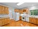 Bright kitchen featuring wooden cabinets, white appliances, and hardwood flooring for a classic feel at 5939 Florasaline Dr, Mebane, NC 27302