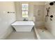 Bright bathroom features a soaker tub and shower stall with tasteful neutral tiling at 6501 Burnette Flower Way, Raleigh, NC 27612