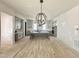 Open concept kitchen features a central island and pendant lighting, wood floors, and shaker style cabinets at 6501 Burnette Flower Way, Raleigh, NC 27612