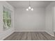 This dining room has hardwood floors and a hanging chandelier with a window providing natural light at 6604 Frogstool Ln, Raleigh, NC 27610