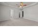 Spacious main bedroom with tray ceiling, carpet, and open doorways to more rooms at 6604 Frogstool Ln, Raleigh, NC 27610