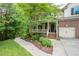Attractive front yard with lush landscaping leading to a charming brick home with a covered porch at 776 Legend Oaks Dr, Chapel Hill, NC 27517
