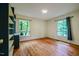 A well-lit bedroom with hardwood floors and two windows overlooking green foliage at 803 Churchill Dr, Chapel Hill, NC 27517